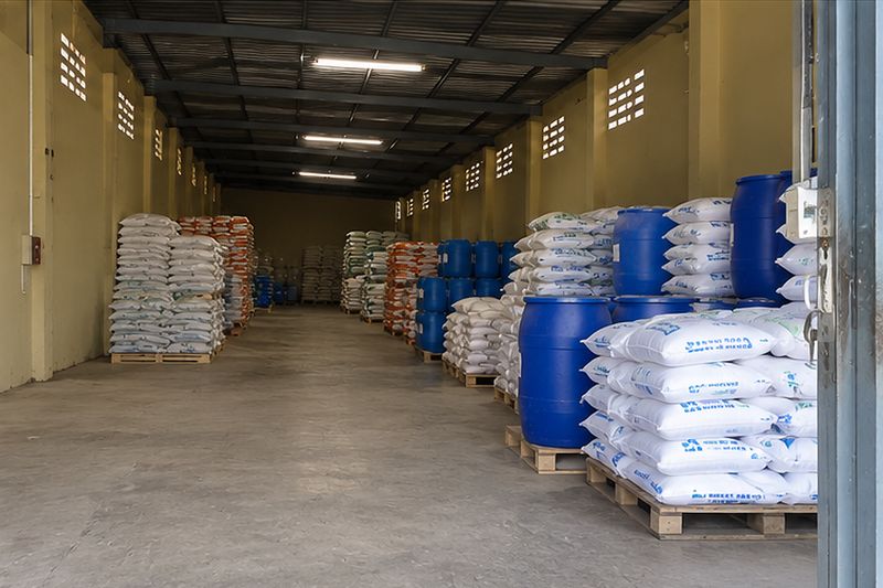 Inside a Suraj Chemicals warehouse in Chennai: palletised bags and drums either side of a clear central aisle